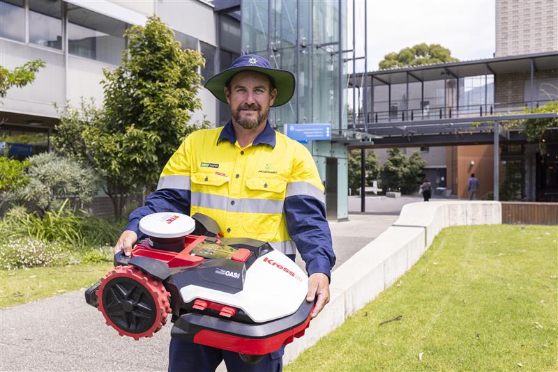 an open space maintenance professional holding a lawn mower